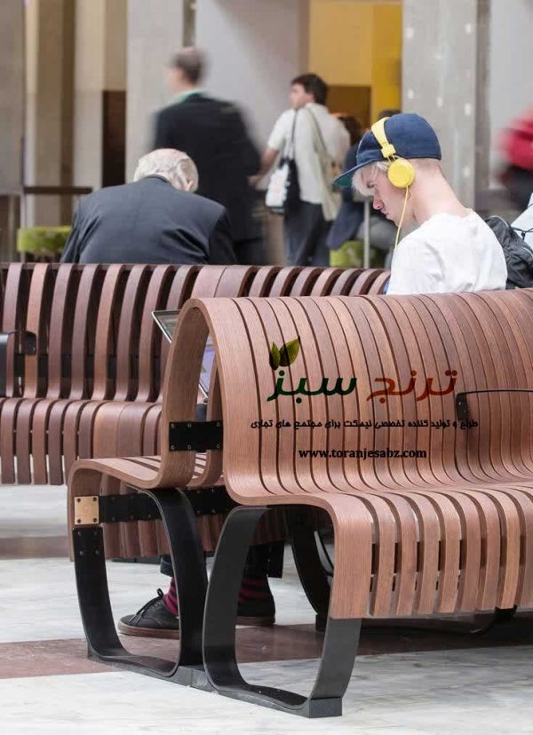 نیمکت با پایه فلزی و رویه و پشتی چوب منخنی در داخل مرکز خرید